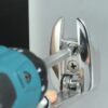 A stainless steel fender hook being attached to a boat with an electric drill.